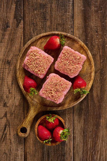 Strawberry Shortcake Blondie with freeze-dried strawberries, vanilla glaze, and golden Oreo crumbs, showcasing a soft, buttery texture and fruity, creamy layers